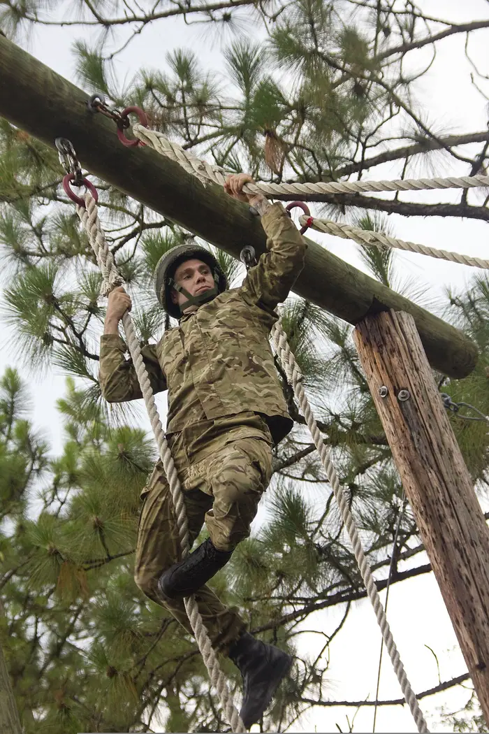 British Parachute Regiment soldier climbing a timber obstacle during a US military exercise